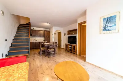 a kitchen with a dining room table and a staircase at Appartamento Dolomiti Alleghe in Alleghe