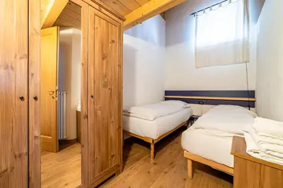 two beds in a small room with a window at Appartamento Dolomiti Alleghe in Alleghe