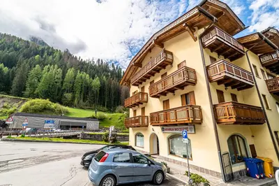 a yellow building with cars parked in a parking lot at Appartamento Dolomiti Alleghe in Alleghe