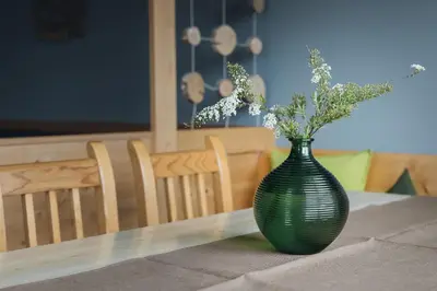 a green vase on a table with flowers in it at Mandlerhof in Verano