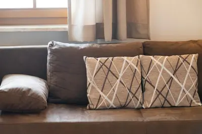 a brown couch with two pillows on it at Wolkanhof Vineyard Apartments in Appiano sulla Strada del Vino