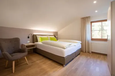 a bedroom with a bed and a chair and a window at Wolkanhof Vineyard Apartments in Appiano sulla Strada del Vino