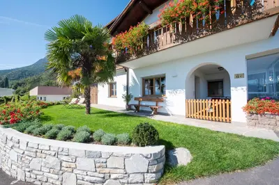 a house with a retaining wall and a palm tree at Wolkanhof Vineyard Apartments in Appiano sulla Strada del Vino
