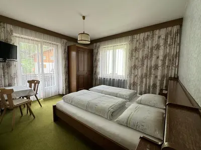 a bedroom with a large bed and a table at APARTMENTS Gasser in Monguelfo