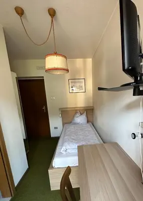 a small bedroom with a bed and a television at APARTMENTS Gasser in Monguelfo