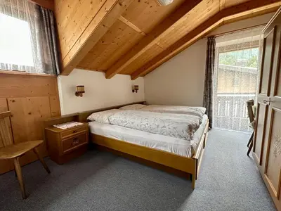 a bedroom with a bed in a room with wooden ceilings at APARTMENTS Gasser in Monguelfo