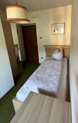 a small room with a bed and a table at APARTMENTS Gasser in Monguelfo