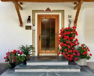 a front door of a house with red flowers at APARTMENTS Gasser in Monguelfo