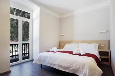 a white bedroom with a large bed with white pillows at Hotel Croda Rossa in Carbonin