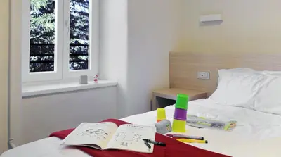 a bedroom with a bed with a book and markers at Hotel Croda Rossa in Carbonin