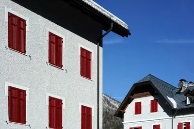 a white building with red shuttered windows on it at Hotel Croda Rossa in Carbonin