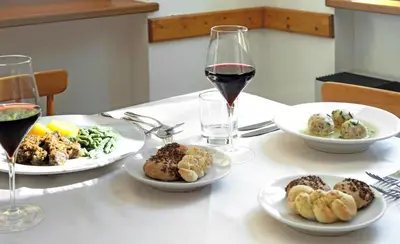 a table with plates of food and a glass of wine at Hotel Croda Rossa in Carbonin