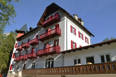 a large white building with red balconies on it at Hotel Croda Rossa in Carbonin