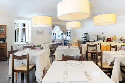 a restaurant with white tables and chairs and chandeliers at Hotel Croda Rossa in Carbonin