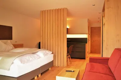 a bedroom with a bed and a red couch at Kastelart - Karbon in Castelrotto