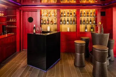 a bar with red walls and bottles of wine at Pension Hasslhof in Caldaro