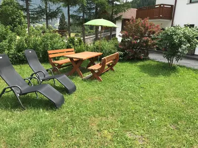 a picnic table and chairs with an umbrella in the grass at Ottohof - Morgenrot in Brennero