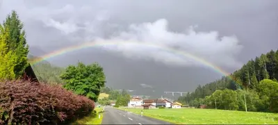 a rainbow in the sky over a road at Ottohof - Morgenrot in Brennero