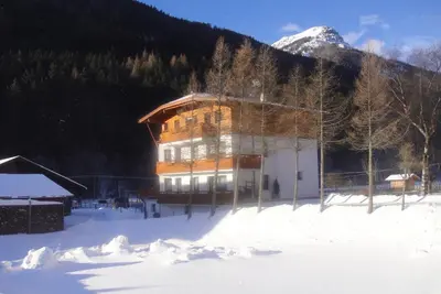 a large building in the snow in front of a mountain at Ottohof - Morgenrot in Brennero