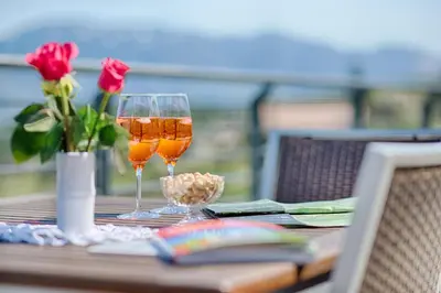 two glasses of wine sitting on a table with roses at Pension Christl in Caldaro