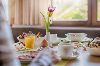 a table with breakfast foods and a flower in a vase at Pension Christl in Caldaro