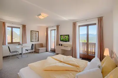 a hotel room with a bed and a living room at Pension Christl in Caldaro