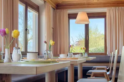 a dining room with two tables with flowers on them at Pension Christl in Caldaro