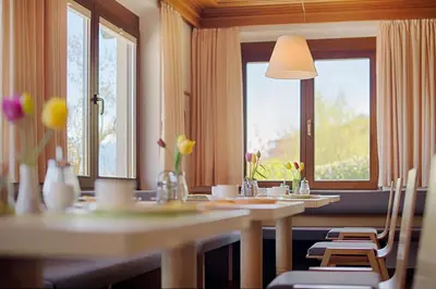 a dining room with tables and windows and flowers at Pension Christl in Caldaro