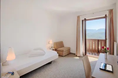 a bedroom with a bed and a window with a balcony at Pension Christl in Caldaro