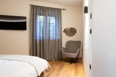 a bedroom with a bed and a chair next to a window at Stadler Hof in Lana