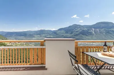 a table and chairs on a balcony with a view of mountains at Goldenhof Penon in Penone