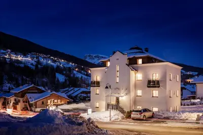 a large white building in the snow at night at Alpin Sport in Ortisei