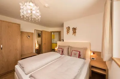 a bedroom with a large white bed with a chandelier at Alpin Sport in Ortisei