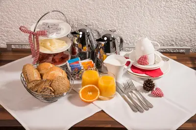 a breakfast table with a basket of bread and orange juice at Alpin Sport in Ortisei