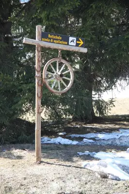 a street sign on a wooden pole in the snow at Alpin Sport in Ortisei