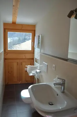 a bathroom with a sink and a toilet with a window at Gruberhof in San Genesio Atesino