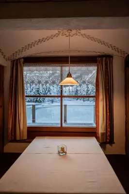a room with a table and a large window at Hotel Lago della Creta in San Vigilio Di Marebbe