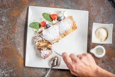 a plate of food with a piece of cake and fruit at Hotel Lago della Creta in San Vigilio Di Marebbe