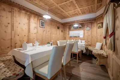a dining room with tables and chairs and wooden walls at Hotel Lago della Creta in San Vigilio Di Marebbe