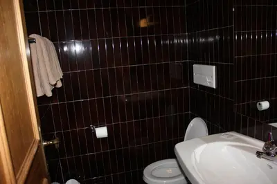a black tiled bathroom with a toilet and a sink at Kehrerhof in Rifiano