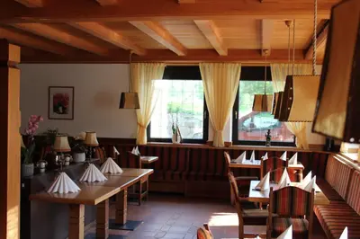 a restaurant with wooden tables and chairs and windows at Kehrerhof in Rifiano