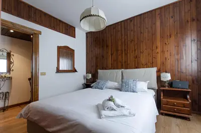 a bedroom with a white bed with a wooden wall at Appartamento centralissimo con wi-fi in Cortina dʼAmpezzo