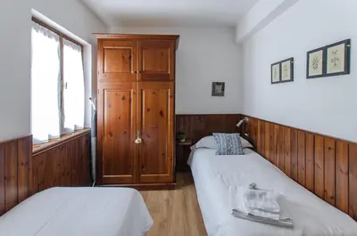 a bedroom with two beds and a wooden door at Appartamento centralissimo con wi-fi in Cortina dʼAmpezzo