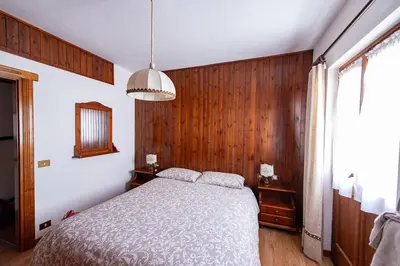 a bedroom with a bed and a wooden wall at Appartamento centralissimo con wi-fi in Cortina dʼAmpezzo