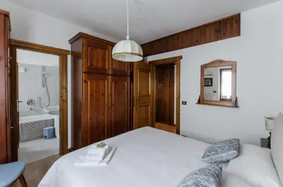 a bedroom with a white bed and a bathroom at Appartamento centralissimo con wi-fi in Cortina dʼAmpezzo