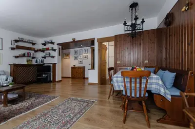 a living room with a table and a kitchen at Appartamento centralissimo con wi-fi in Cortina dʼAmpezzo