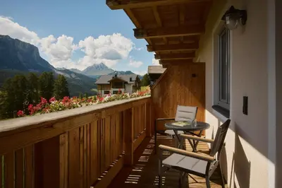 a balcony with a table and chairs and a view of mountains at Residence Rosarela in Badia