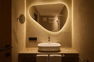 a bathroom with a sink and a round mirror at Residence Rosarela in Badia