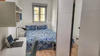 a small bedroom with a bed and a desk with a laptop at Bolzano 2-Room Central Mountain View, WiFi Netflix AC Lift in Bolzano