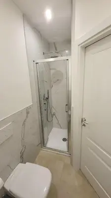 a white bathroom with a shower and a toilet at Bolzano 2-Room Central Mountain View, WiFi Netflix AC Lift in Bolzano